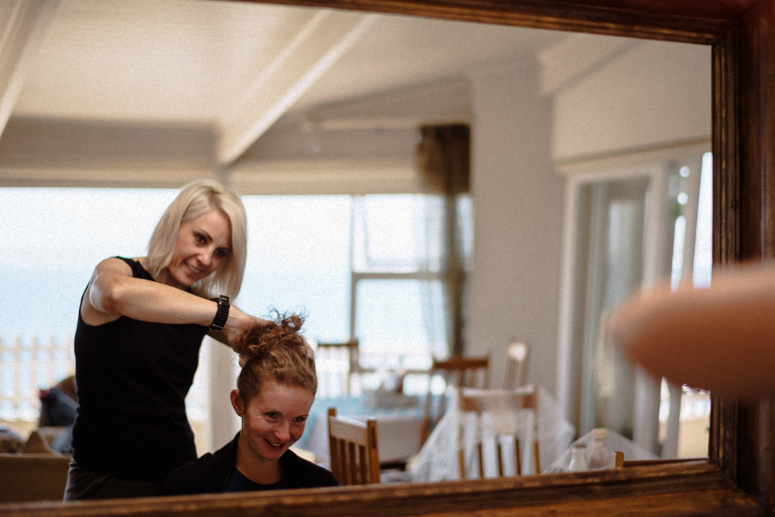 Friseurin steckt der Braut die Haare hoch, gesehen im Spiegel