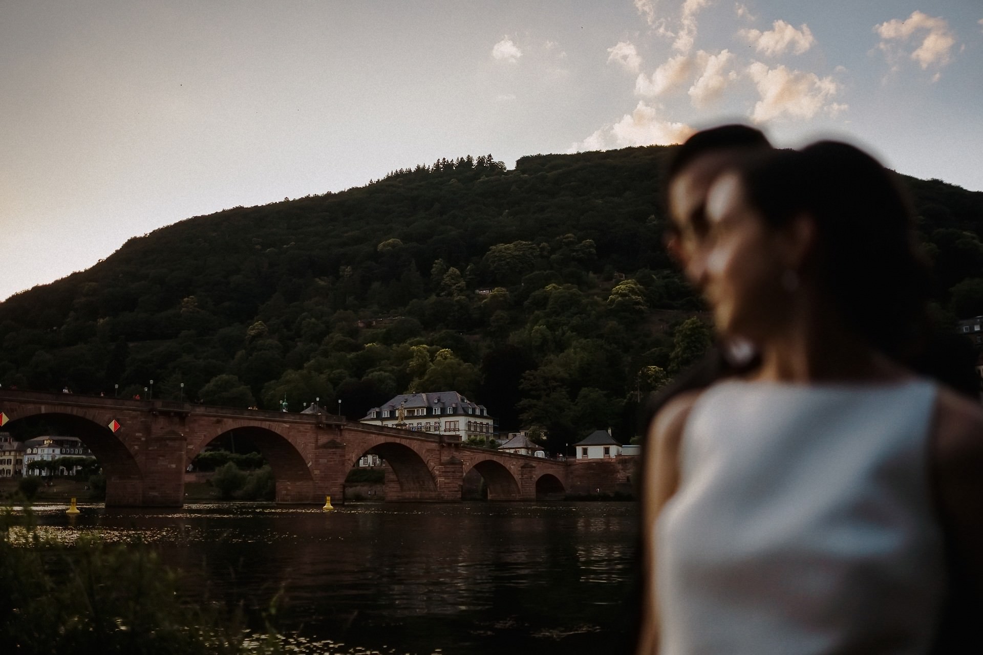 Braut im Abendlicht am Neckarufer, dahinter die Alte Brücke.