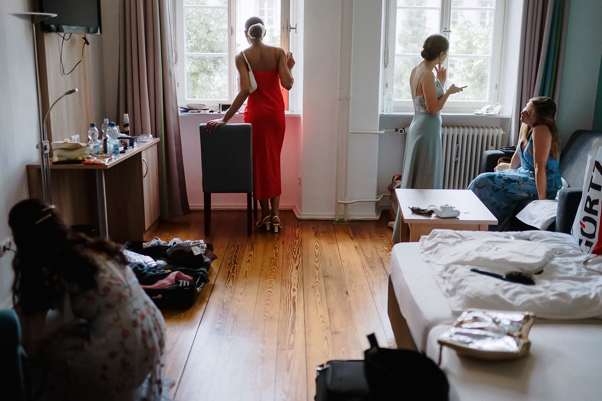 Brautjungfern im turbulenten Hotelzimmer beim gemeinsamen Ankleiden vor der Trauung.