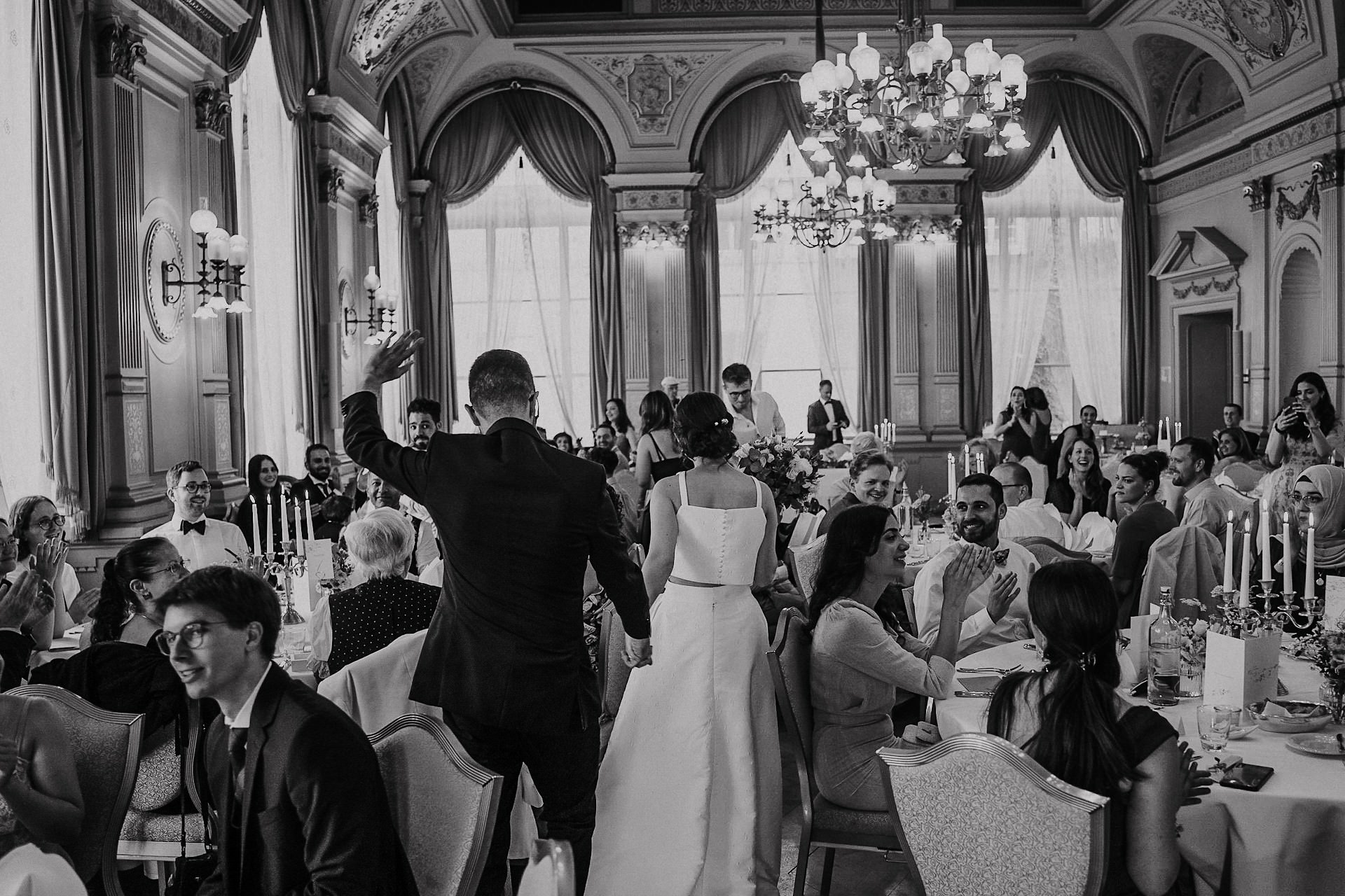 Hochzeitsgäste empfangen Brautpaar im eleganten Festsaal des Palais.