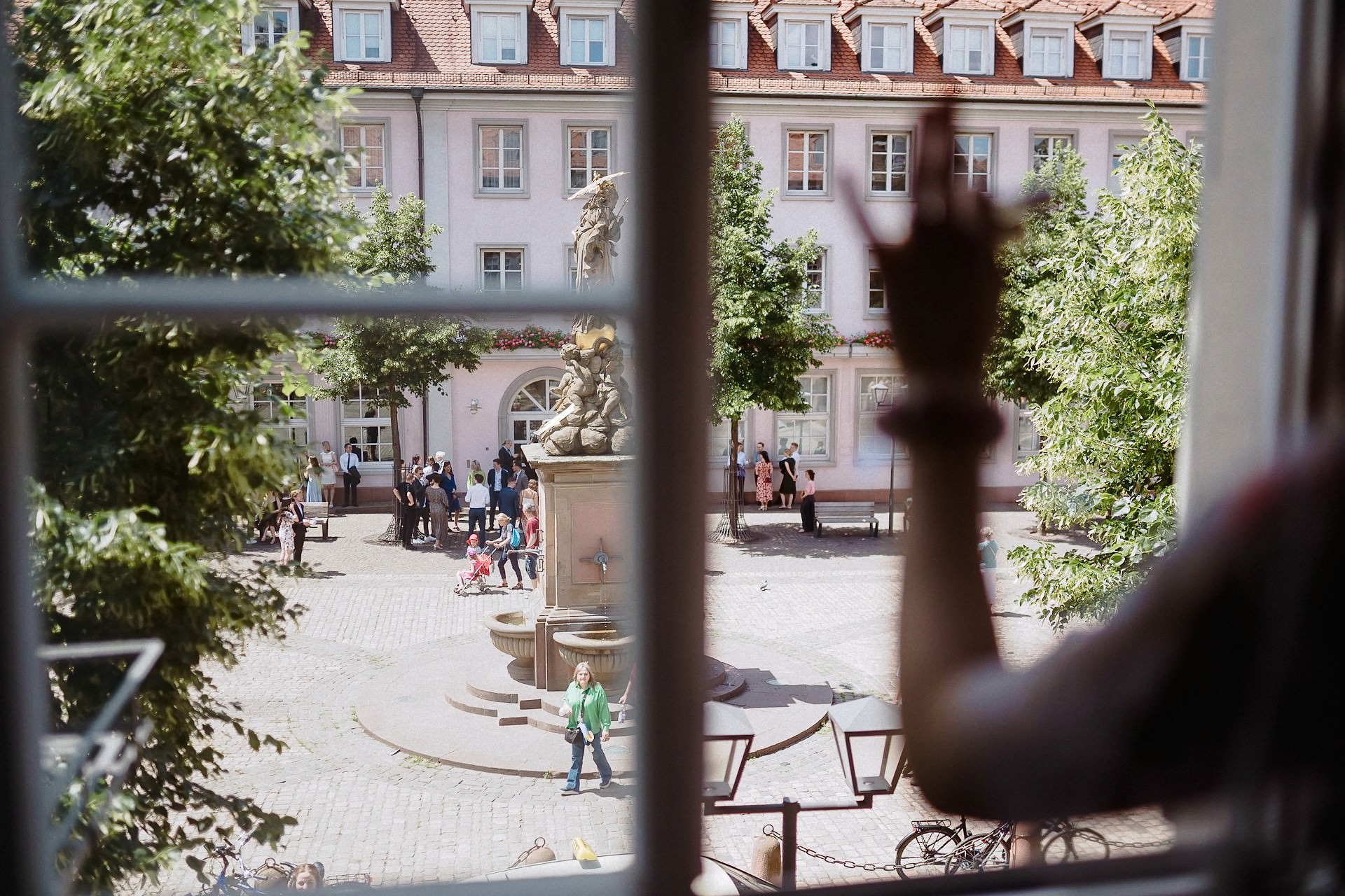 Blick aus Fenster auf Palais-Hof mit Hochzeitsgästen, historisches Gelände.