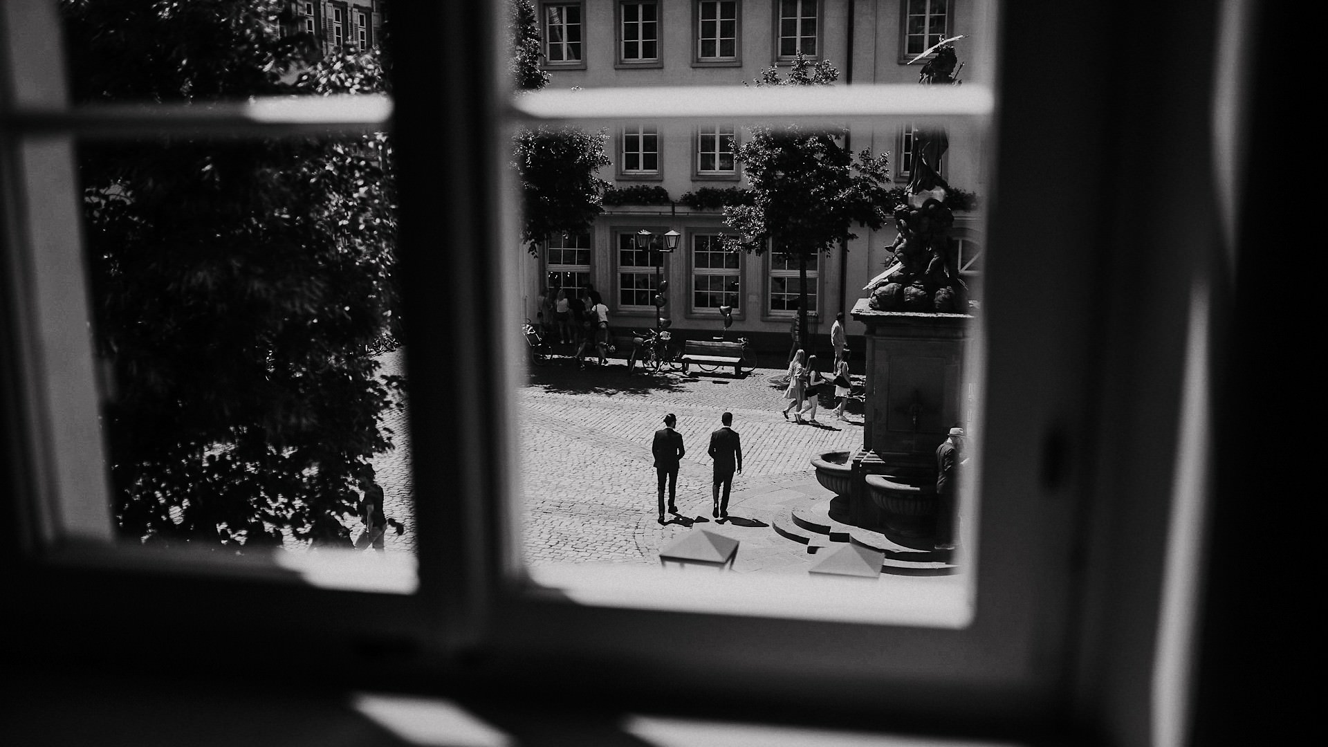 Blick aus dem Fenster auf zwei Gäste in Anzügen am Brunnen des Kornmarkts.