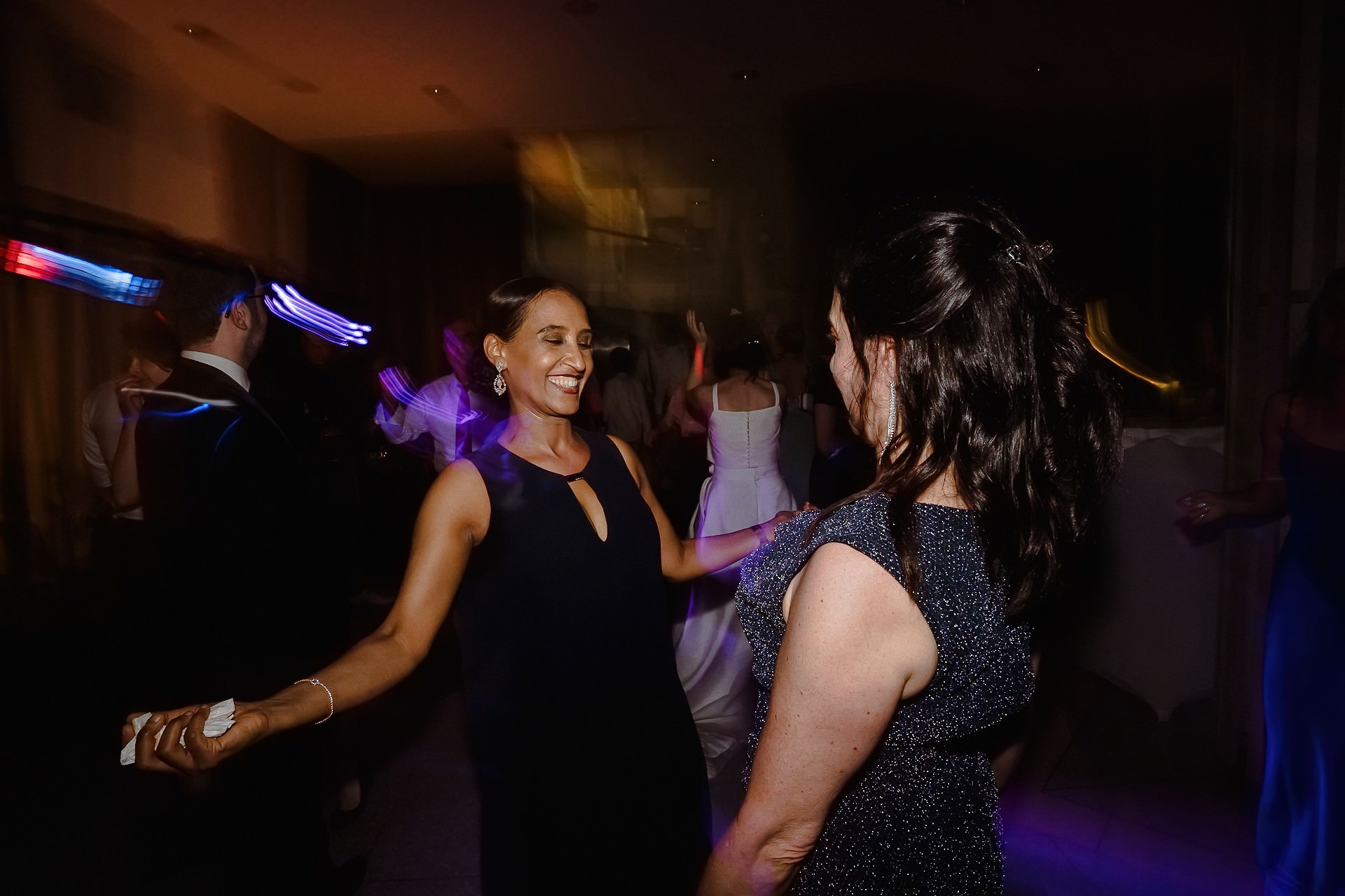 Hochzeitsgäste mit Neon-Fächern und weißen Fächern bei Tanzparty.