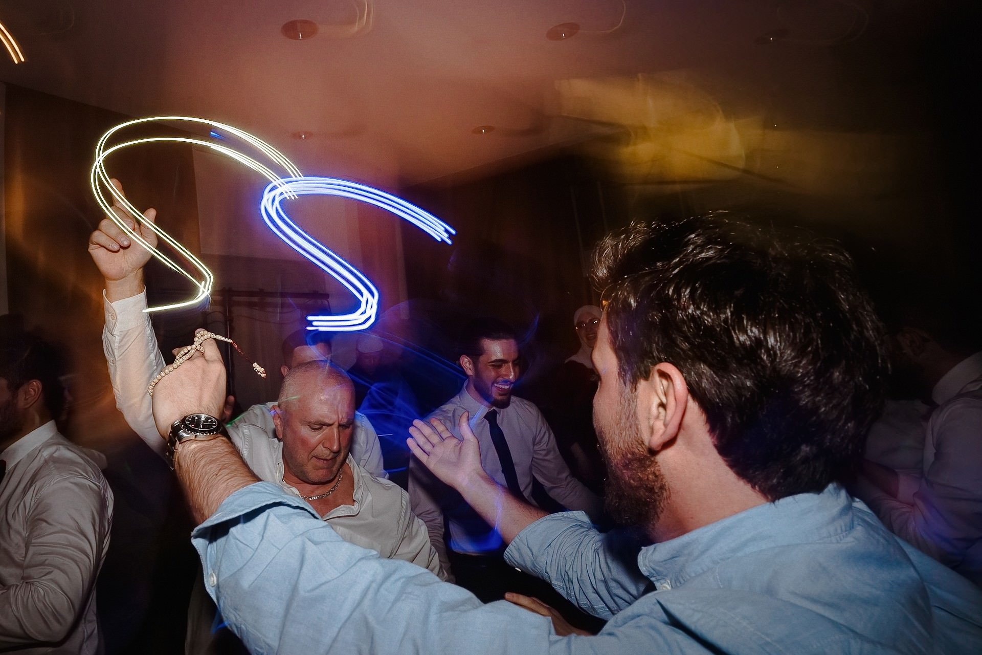 Hochzeitsgäste tanzen mit roten und goldenen Neon-Lichteffekten.
