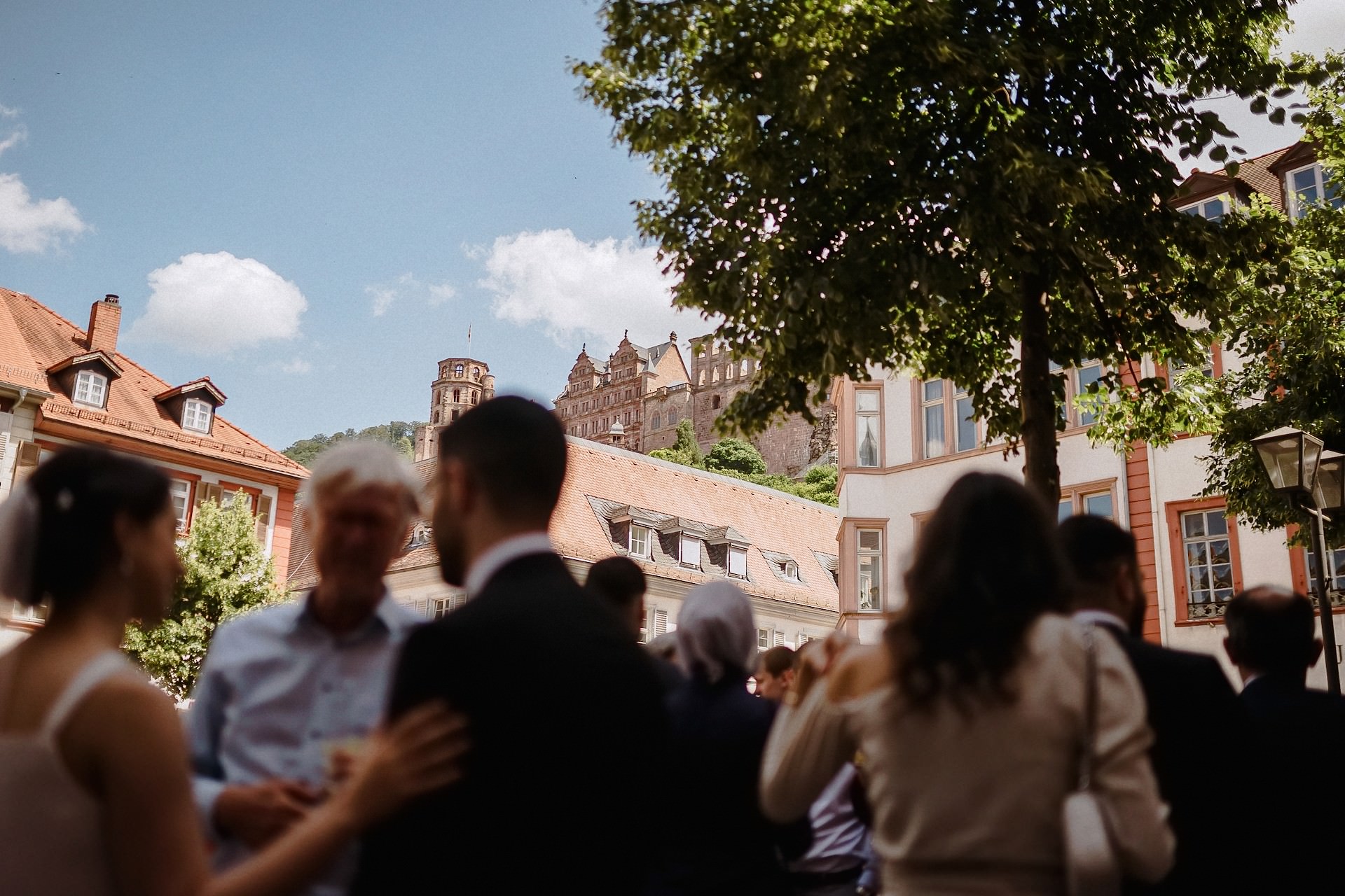 Hochzeitsgäste sammeln sich auf Palais-Platz, Heidelberg Schloss sichtbar.