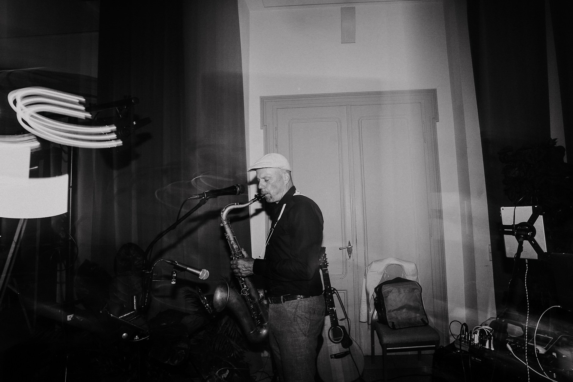 Saxophonist spielt auf Bühne während Hochzeitsfest, Neonlicht oben.