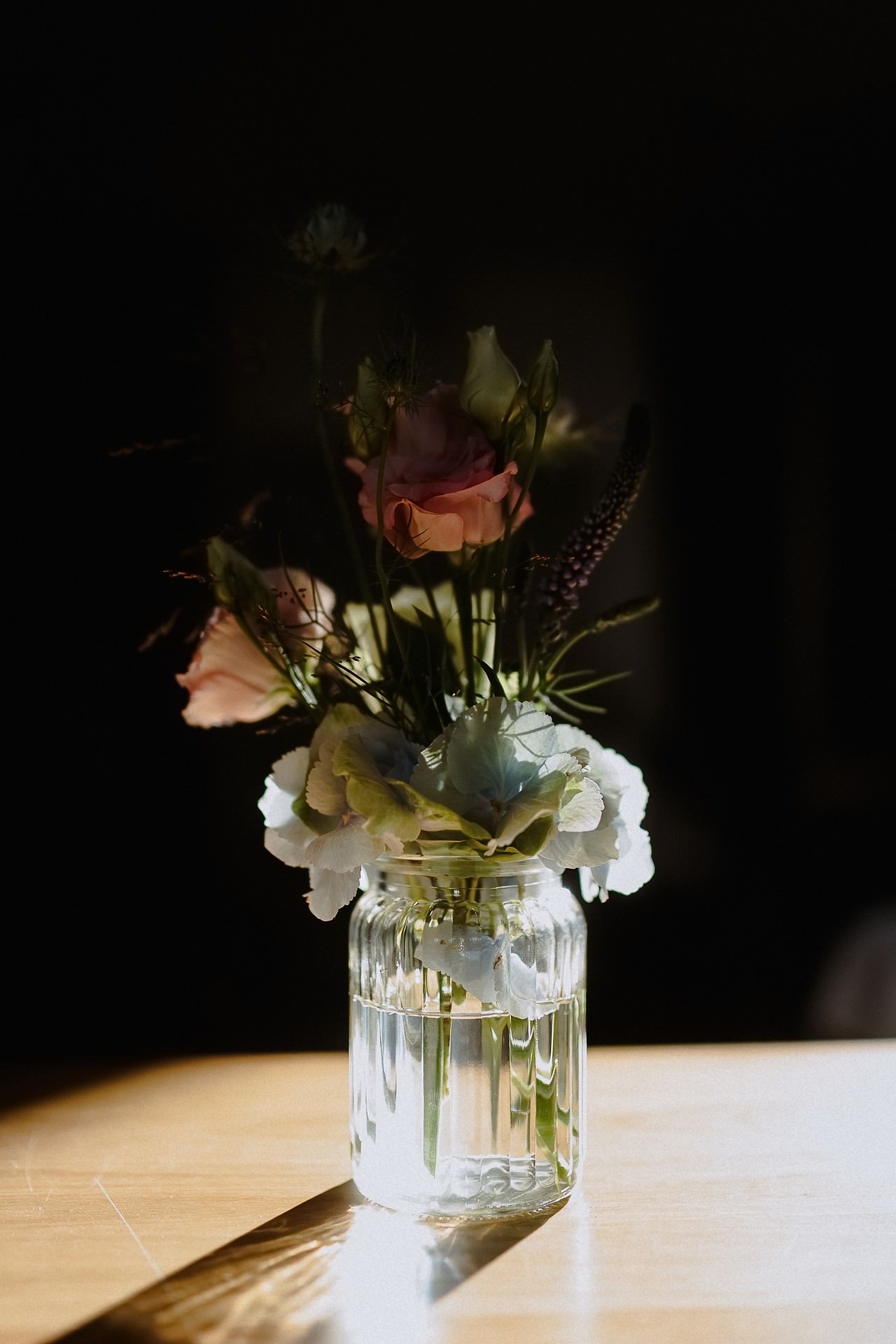 Hochzeits-Tischdekoration mit roten und weißen Blumen in Kristallvase.