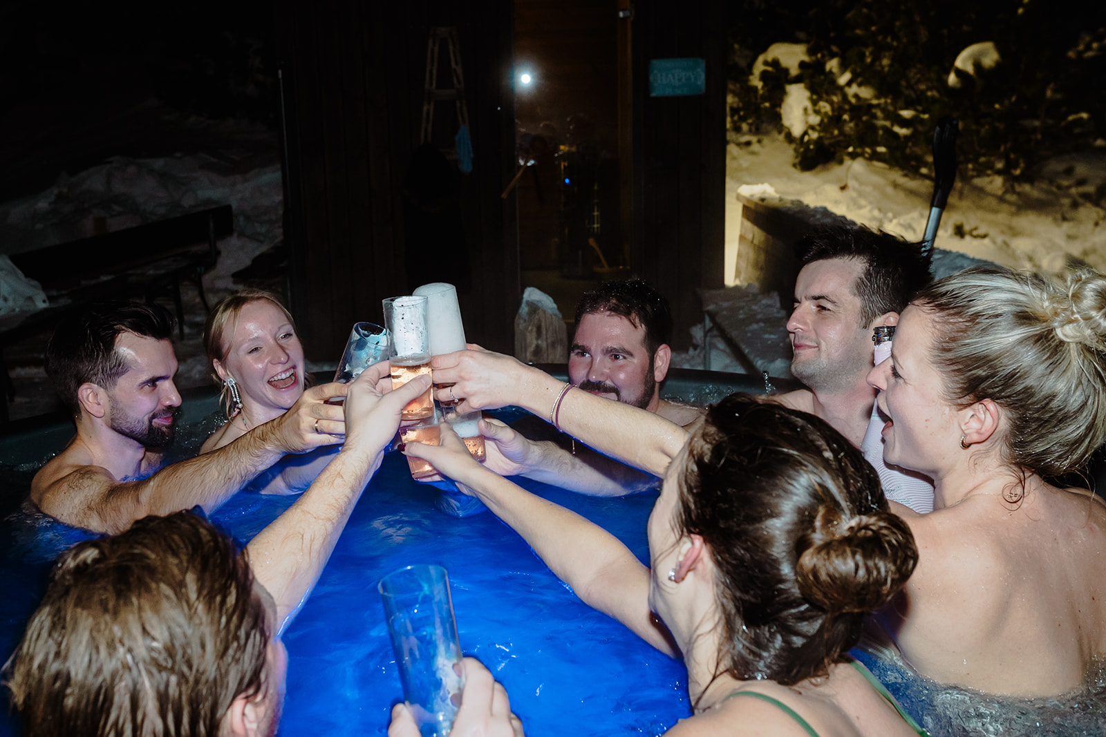 Die Hochzeitsgesellschaft stößt nachts im Whirlpool im Schnee an