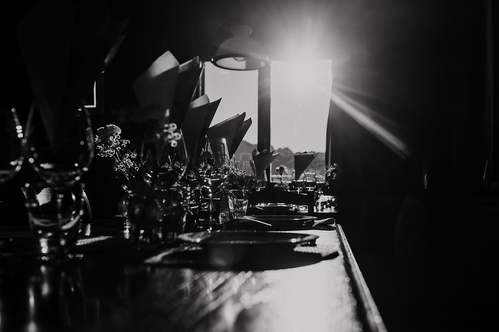 Weingläser und gefaltete Servietten auf der gedeckten Tafel im Gegenlicht der Berge