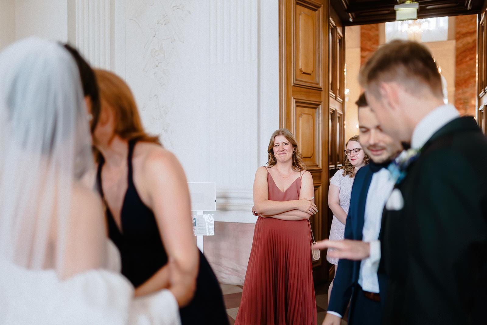 Gratulationen nach der Trauung, eine Freundin im weinroten Kleid wartet