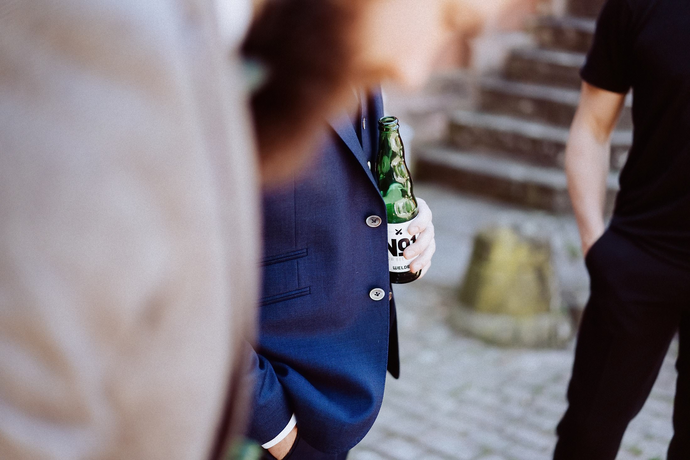 Bierflasche in der Hand des Bräutigams, fokussierte Nahaufnahme.