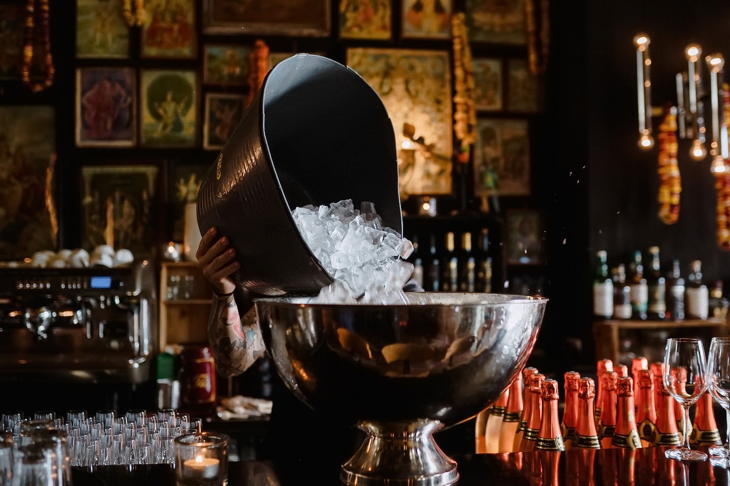 Ein Barkeeper schüttet Eiswürfel in die silberne Sektschale an der Bar