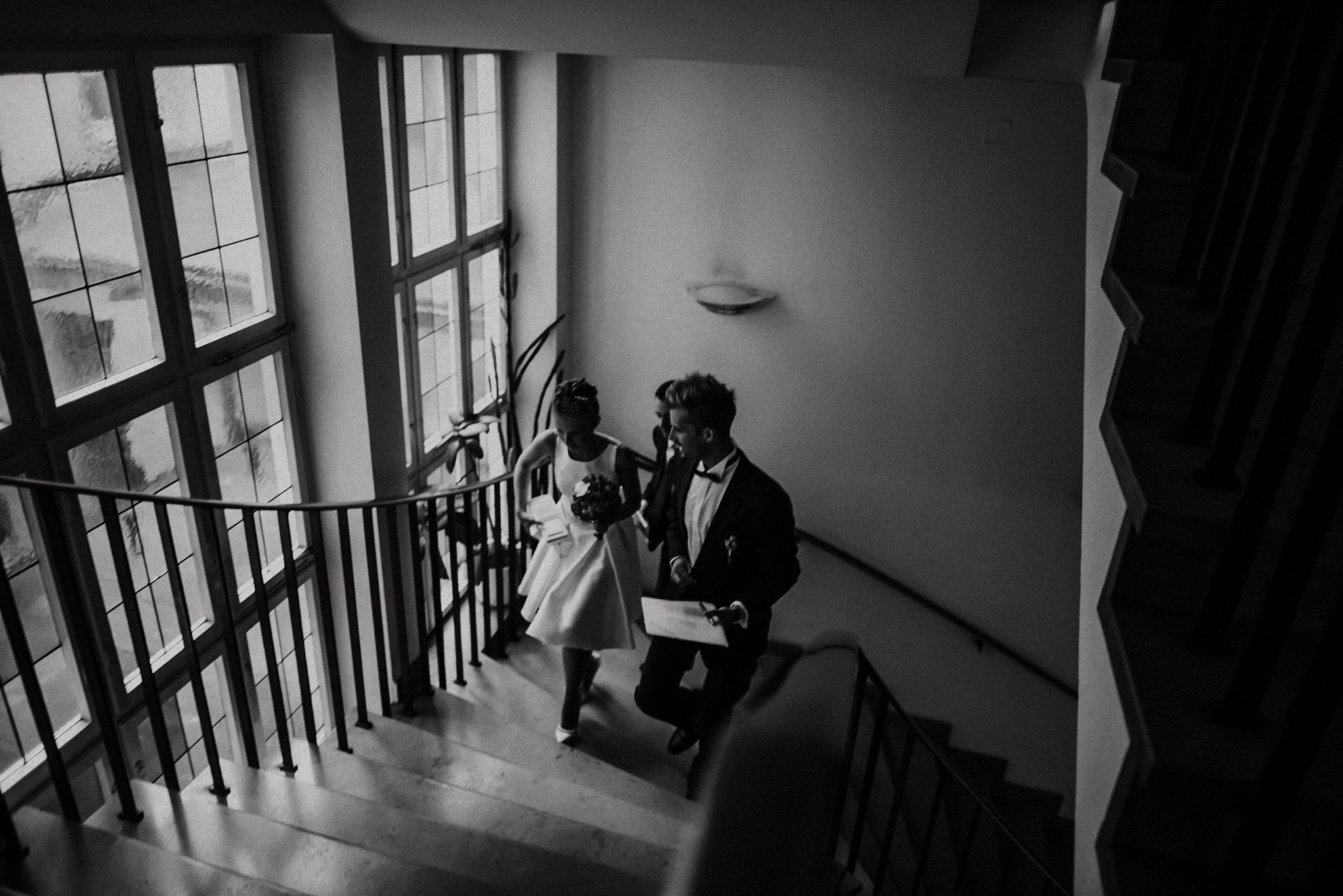 Brautpaar steigt die Treppe im Alten Rathaus zum Trauzimmer hinauf, schwarzweiß.