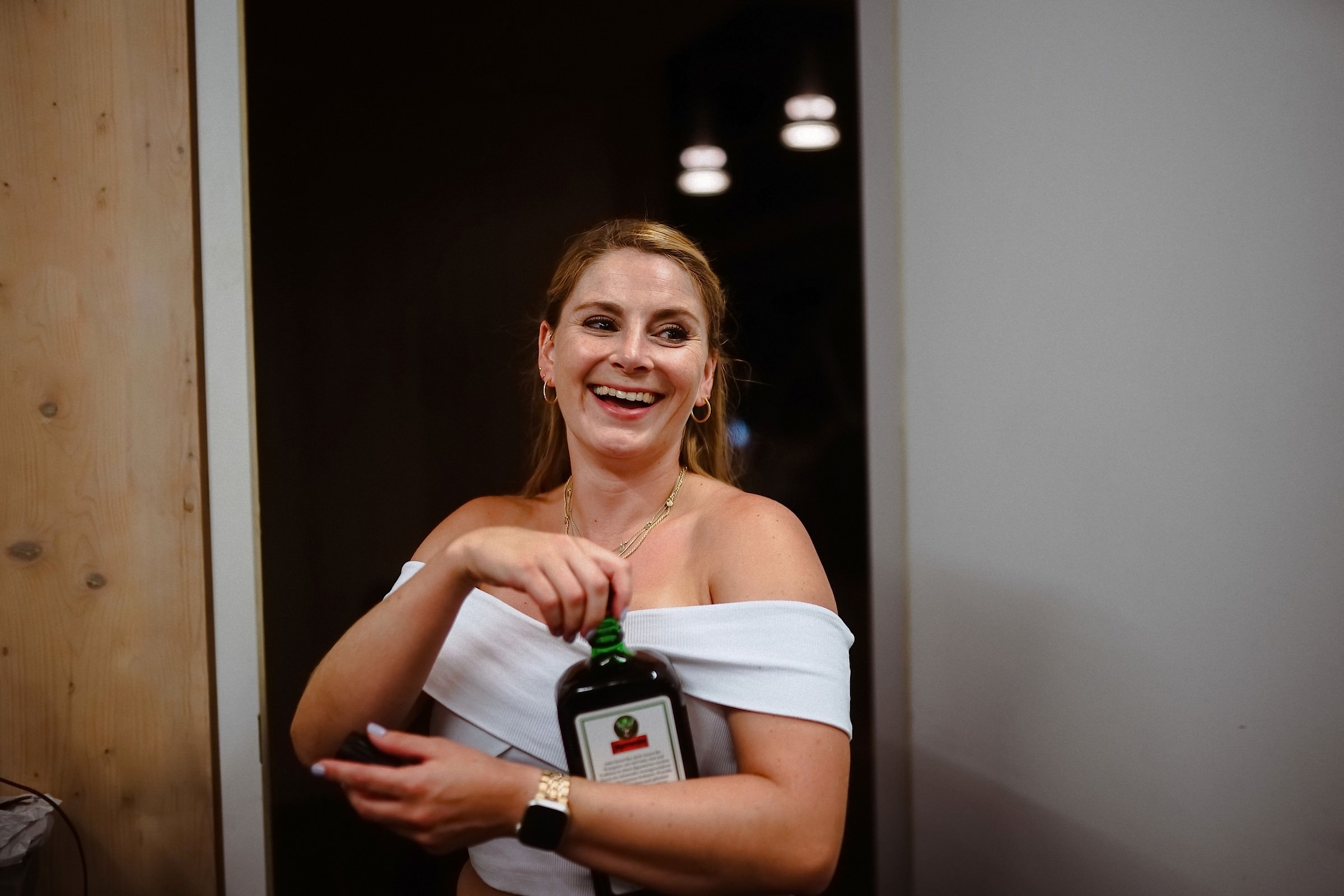 Eine lachende Gästin hält stolz eine Flasche Jägermeister in den Händen.