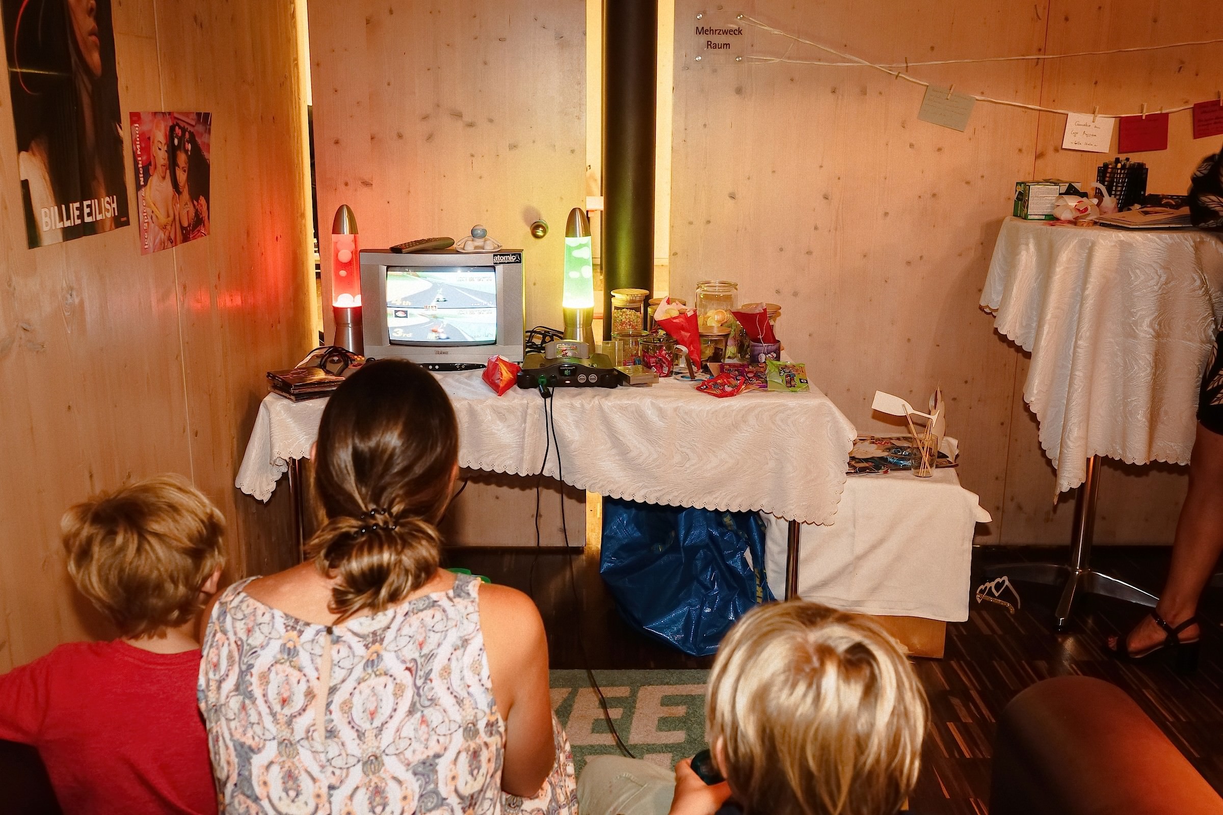 Zwei Kinder sitzen vor einem alten Röhrenfernseher und spielen Mario Kart auf einer Nintendo 64.