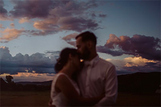 Hochzeitspaar umarmt sich vor dem letzten Licht des Tages, der Himmel ist bunt