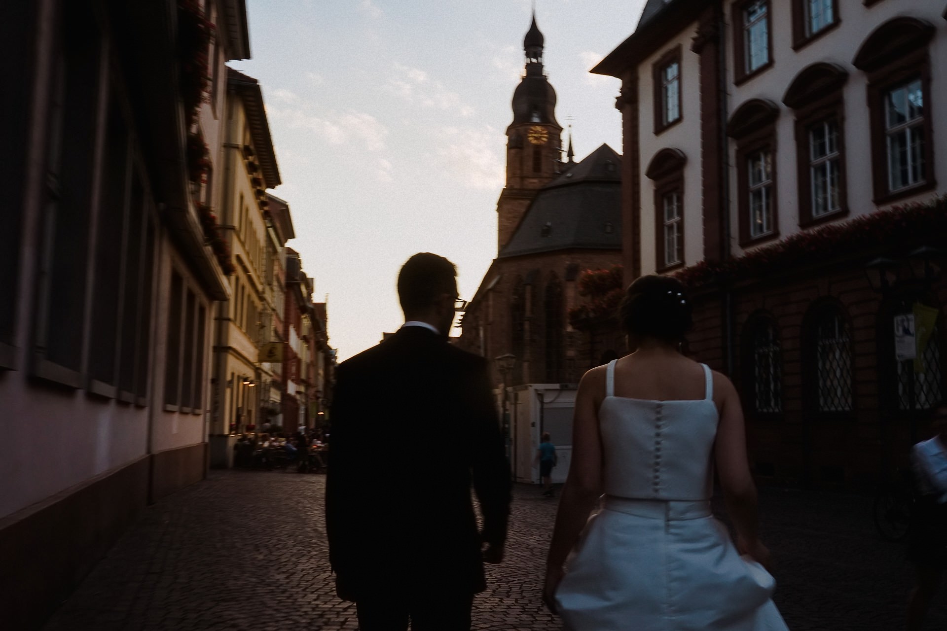 Brautpaar geht Hand in Hand durch die Heidelberger Altstadt bei Sonnenuntergang.
