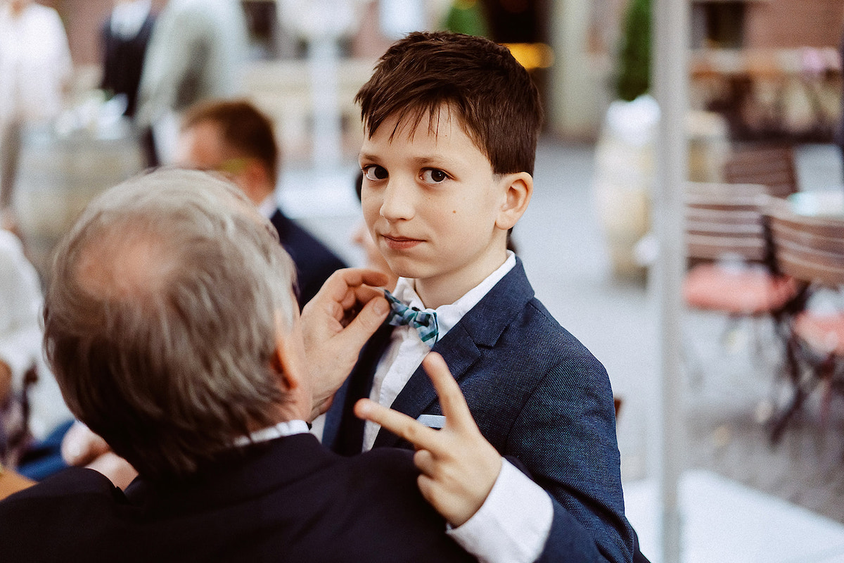 Opa richtet die Fliege bei einem jungen Hochzeitsgast