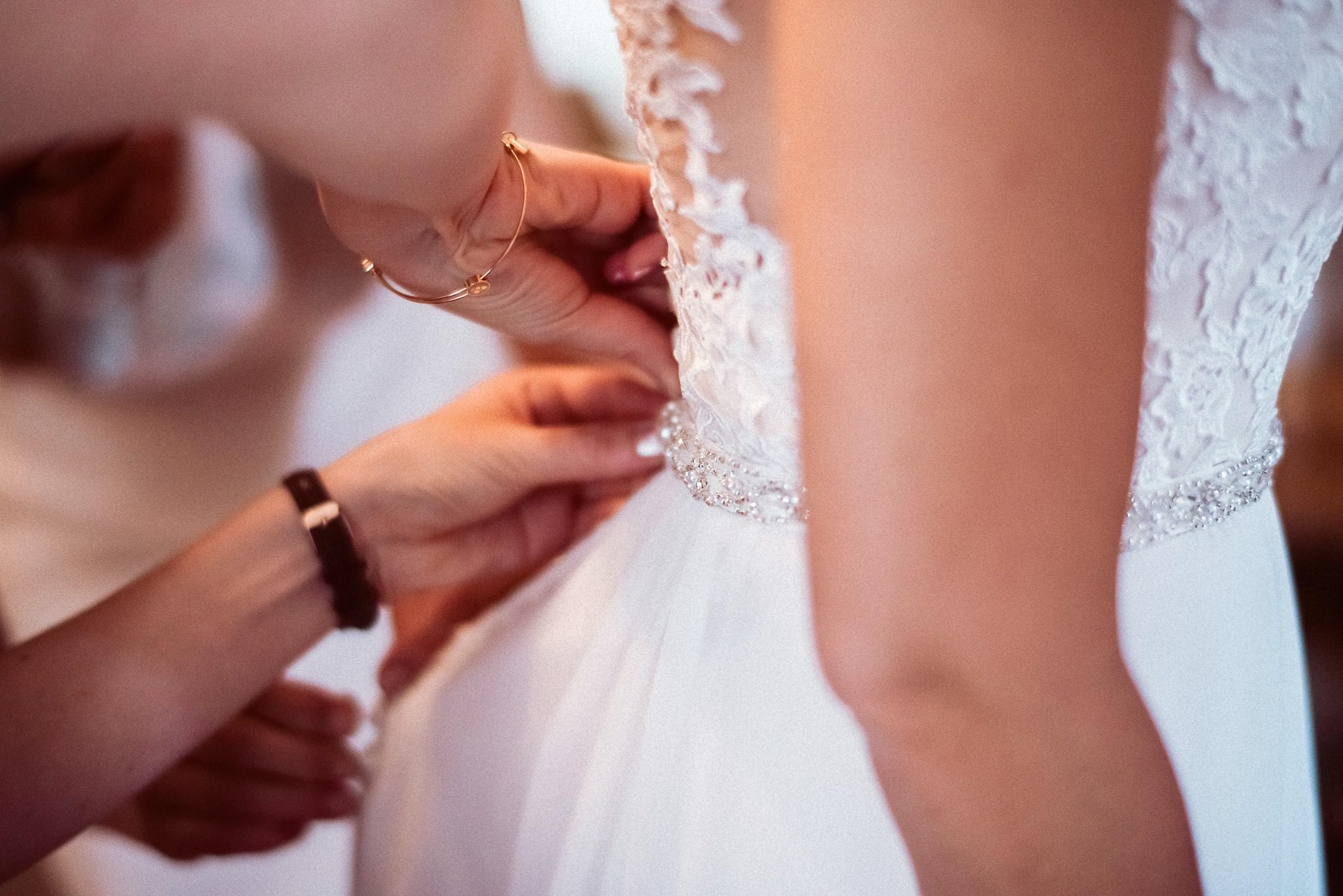 Ein Detail zeigt das Spitzenkleid der Braut mit ihrem Brautkranz-Schmuck.