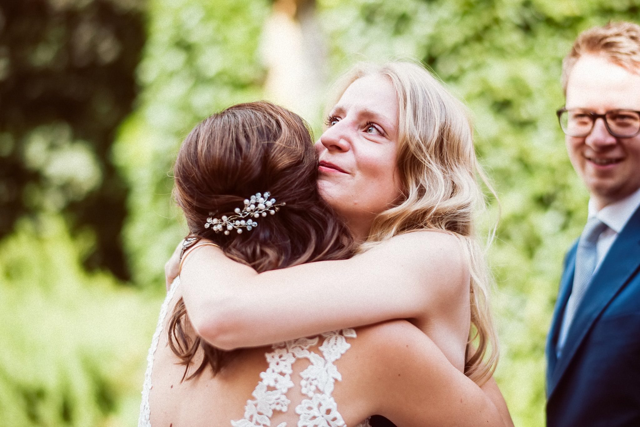 Eine Freundin umarmt die Braut zur Gratulation nach der Hochzeit.