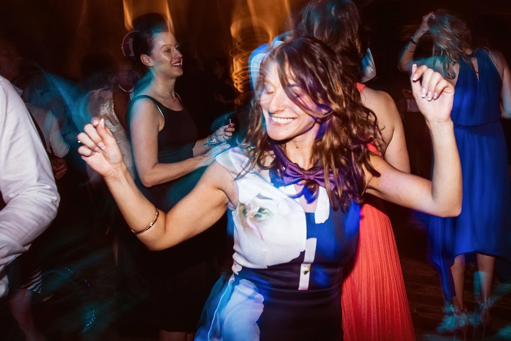 Eine Gästin tanzt ausgelassen mit fliegenden Haaren im bunten Partylicht.