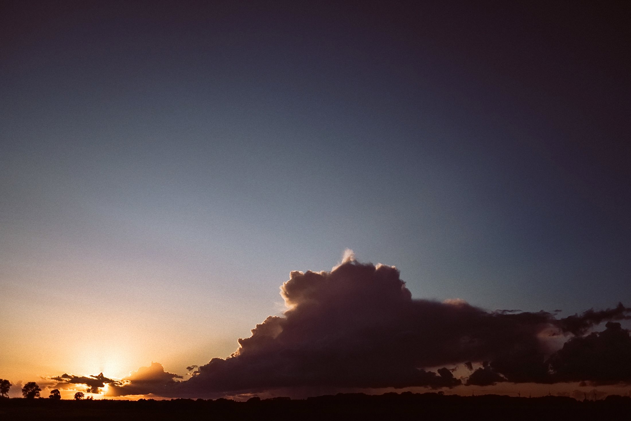 Dramatischer Sonnenuntergang mit Wolken am Horizont beim Abendlicht.