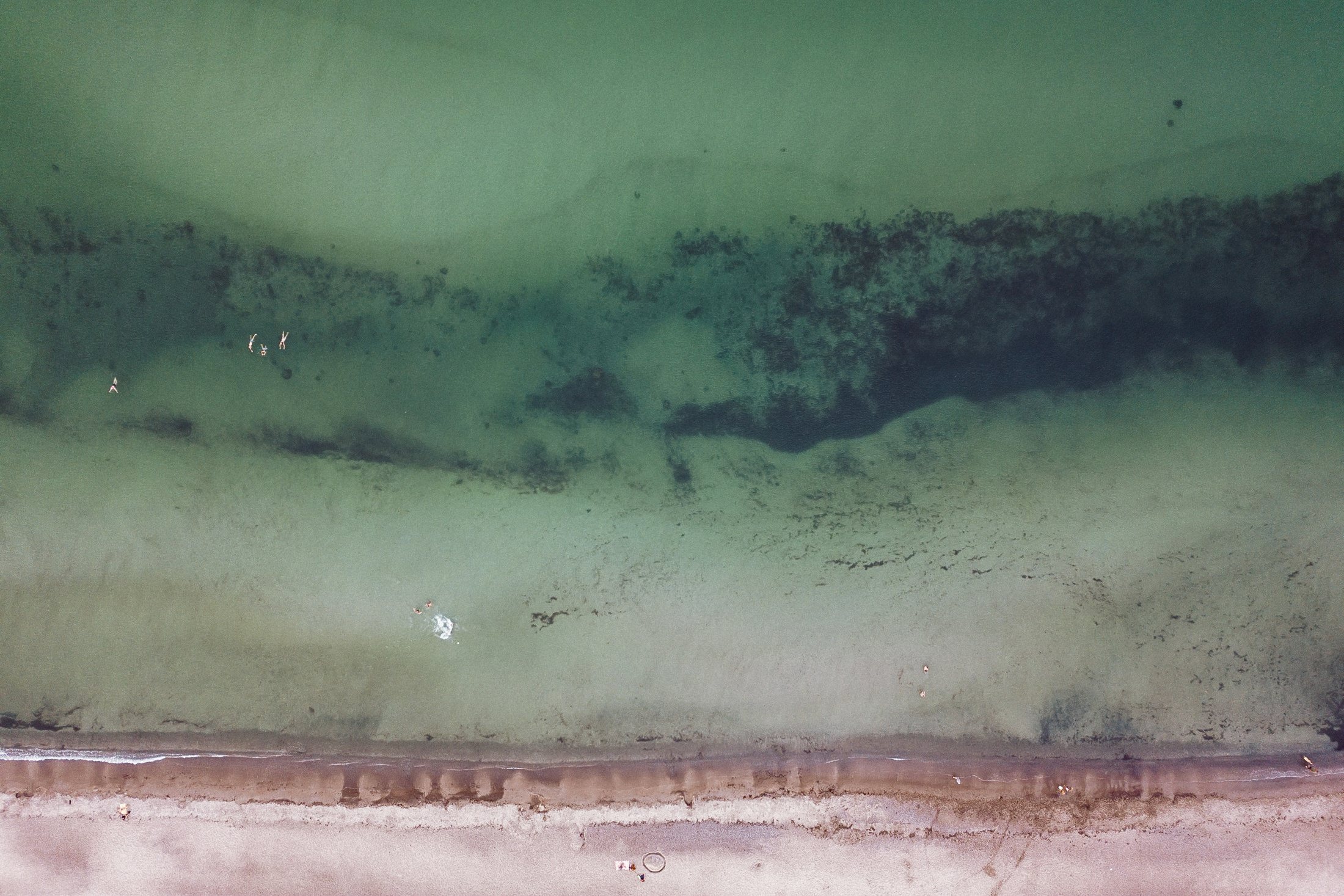 Luftaufnahme der Ostseeküste mit feinsandigem Strand und türkisem Wasser.
