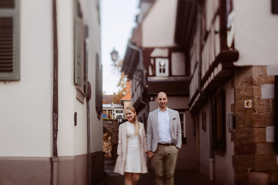Brautpaar läuft hand in hand durch alte Deidesheimer Gasse mit Fachwerk.
