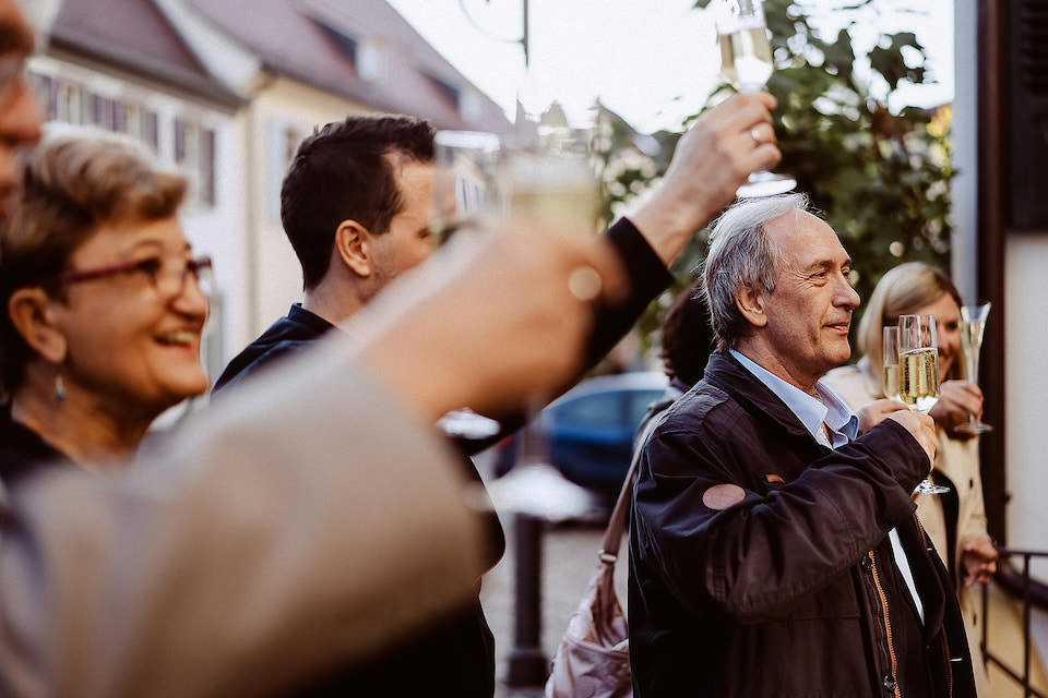 Gäste stoßen mit Sekt vor dem Rathaus auf das Brautpaar an.
