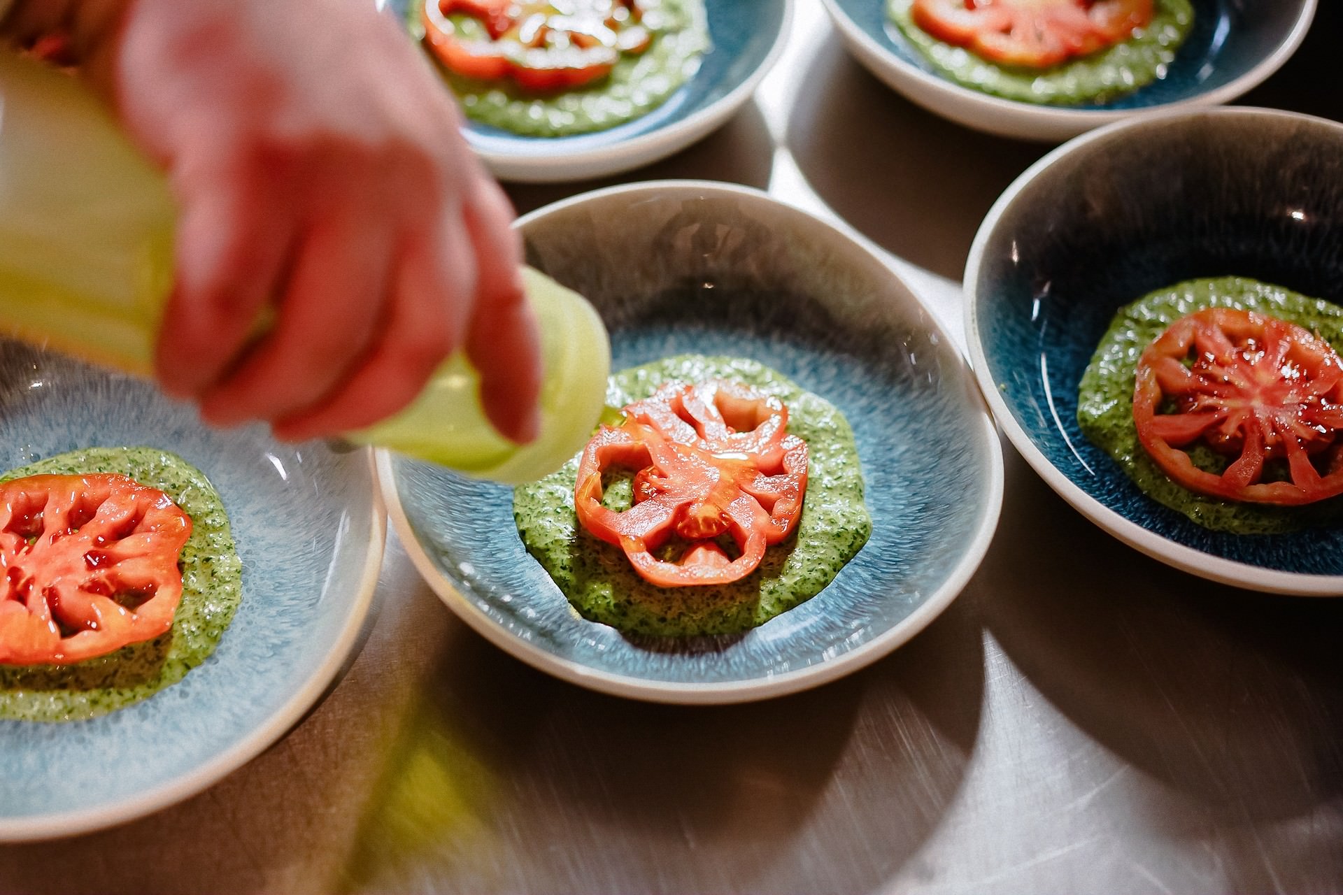 Chef serviert grüne Vorspeise mit Tomaten in der Küche.