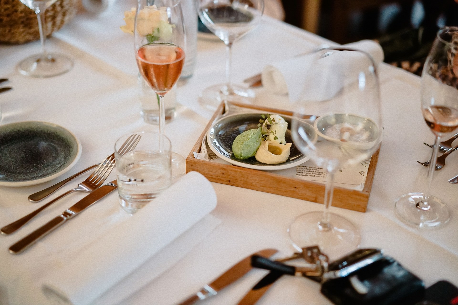 Gast genießt Aperitif mit Vorspeise auf weißem Tisch.