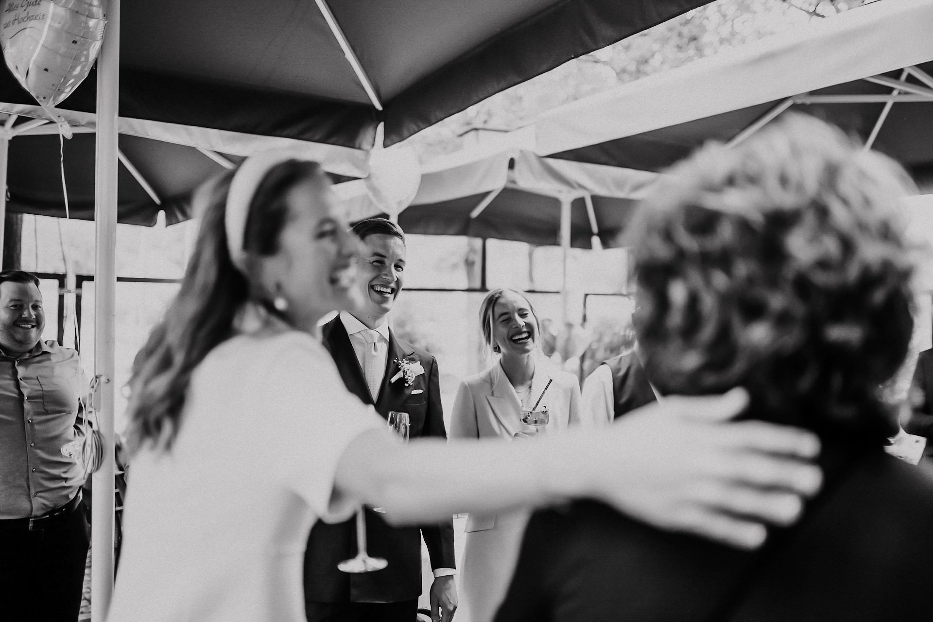 Gast mit Brille trinkt lächelnd Sekt bei der Hochzeit.
