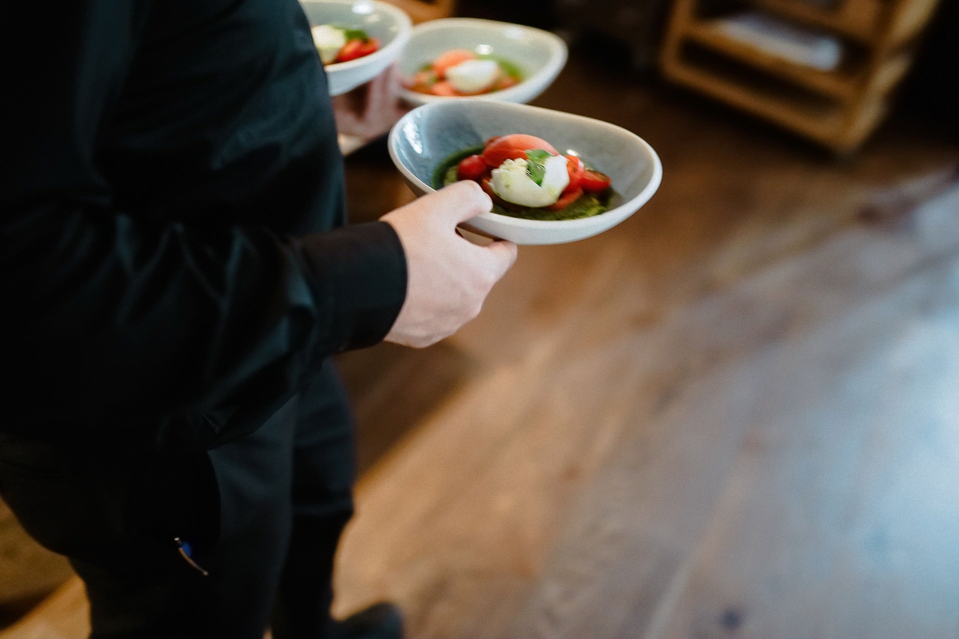 Hand hält weiße Schüssel mit grüner Vorspeise.